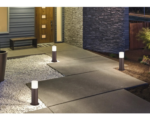 Osvetlený chodník s niekoľkými stĺpikovými svetlami pred domom.