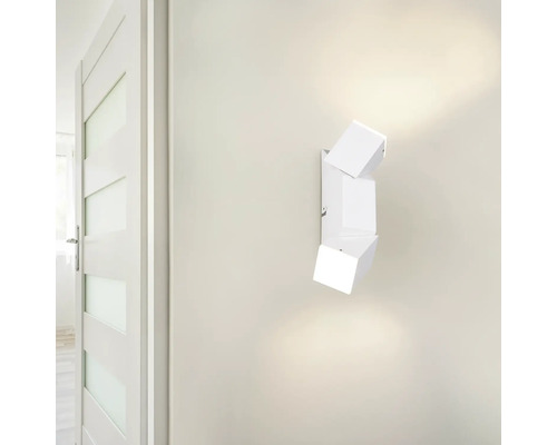 Biele nástenné svietidlo s kubickým dizajnom vedľa dverí