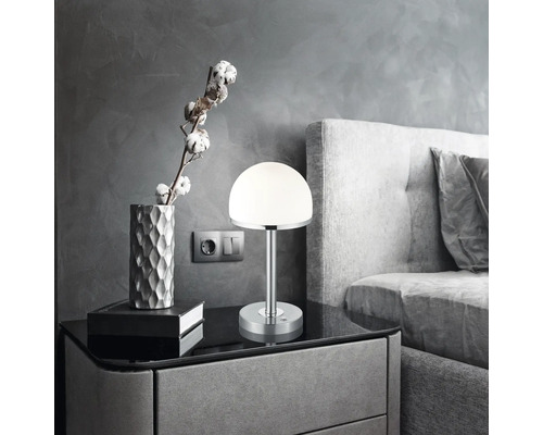 Nočný stolík s lampou, dekoráciou a posteľou v spálni