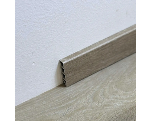 Plastová podlahová lišta s dreveným dekorom na stene a podlahe