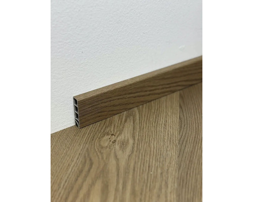 Podlahová lišta s dreveným vzhľadom pri stene