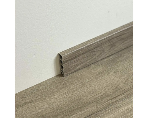 Plastová podlahová lišta s dreveným vzhľadom pri stene