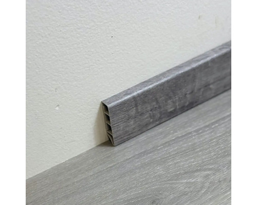 Sivá plastová podlahová lišta na podlahe a na stene