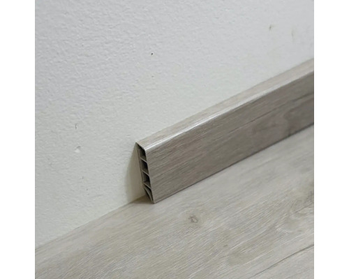 Plastová podlahová lišta s drevenou štruktúrou na stene a podlahe