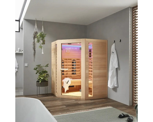 Rohová drevená infra sauna v kúpeľni s vaňou, uterákmi a rastlinami.