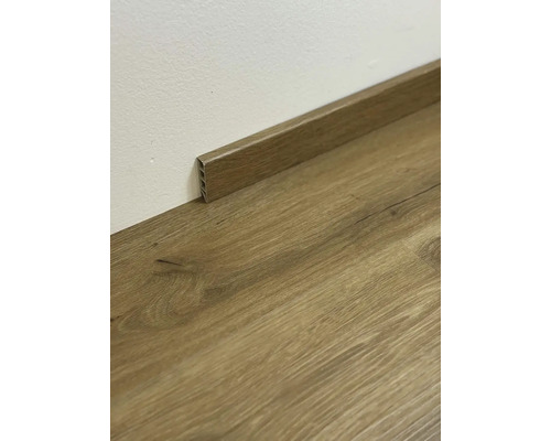 Drevená podlahová lišta na drevenej podlahe pri stene