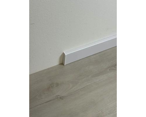 Biela podlahová lišta na stene nad podlahou