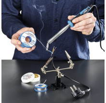 Osoba spájkuje káble spájkovačkou, spájkovacím cínom a spájkovacou pastou na pracovnej ploche.