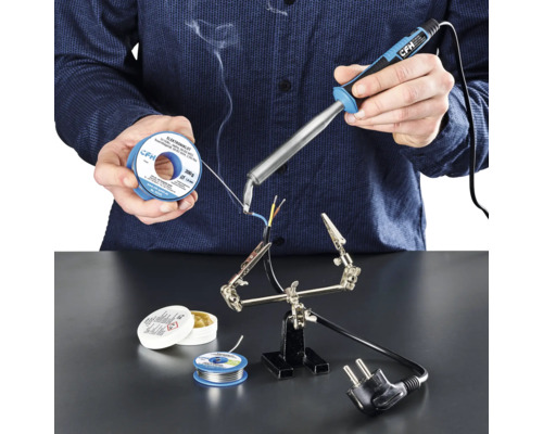Elektrická spajkovačka CFH E 100 Osoba spájkuje káble spájkovačkou, spájkovacím cínom a spájkovacou pastou na pracovnej ploche.