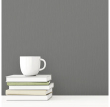 Sivá vliesová tapeta s textilnou štruktúrou vedľa šálky a kníh