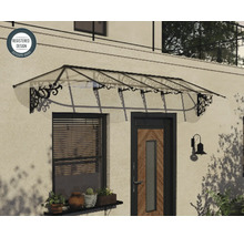 Priesvitná vchodová strieška s čiernymi zdobenými kovovými konzolami namontovaná nad vchodovými dverami a oknom, registrovaný dizajn.