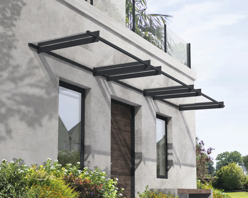 Moderná vchodová strieška s tmavým kovovým rámom a priehľadnými panelmi nad vchodovými dverami a oknami na sivej kamennej fasáde.