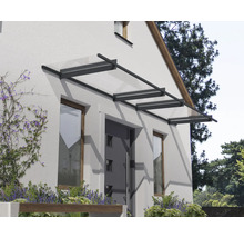 Moderná sklenená strieška s tmavým kovovým rámom nad vchodovými dverami na svetlej fasáde.