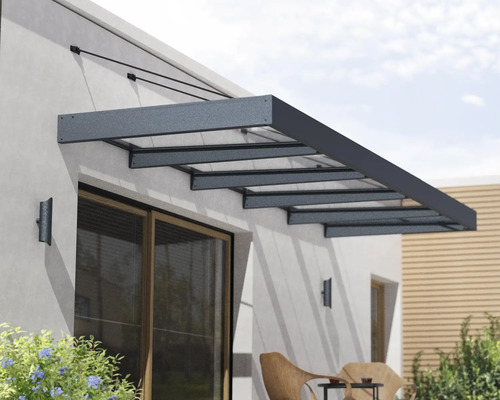 Moderná vchodová strieška z hliníka a skla nad terasovými dverami na stene domu.