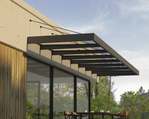Moderné zastrešenie terasy zo skla a tmavého kovu namontované na stenu domu s dreveným obkladom nad vonkajším posedením.
