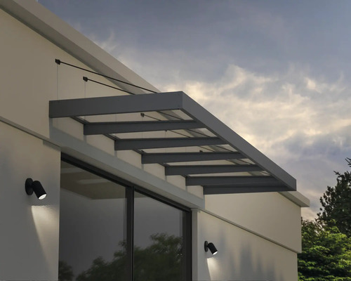 Moderná strieška nad dvere zo skla a sivého kovu s tiahlami namontovaná na bielej fasáde nad oknom.