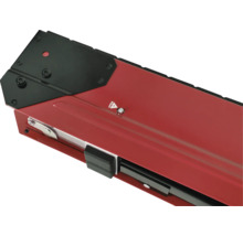 Detailný pohľad na červený držiak okenného parapetu s čiernym krytom a upevňovacími prvkami