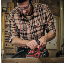 Muž hobľuje drevo elektrickým hoblíkom Einhell v dielni.