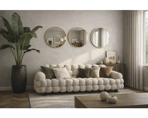 Obývacia izba s čalúnenou pohovkou, ozdobnými vankúšmi, izbovou rastlinou v kvetináči a tromi okrúhlymi zrkadlami na stene.