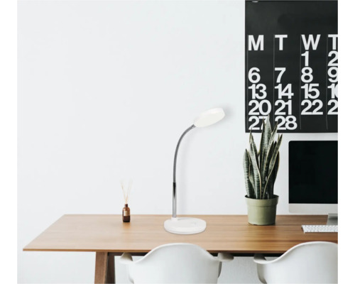 Písací stôl so stolnou lampou, rastlinou a kalendárom