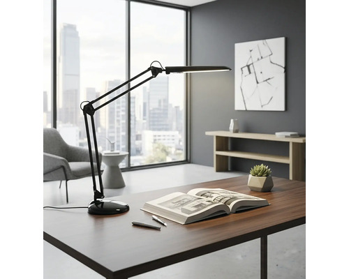 Stôl s lampou s otočným ramenom, knihou a perami vo svetlej kancelárii.