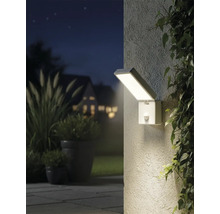 Osvetlený vonkajší záber s obdĺžnikovým nástenným svietidlom so senzorom pohybu vedľa rastlín.