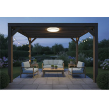 Pergola so záhradným nábytkom, stropným svietidlom a svetelnou reťazou v záhrade za súmraku.