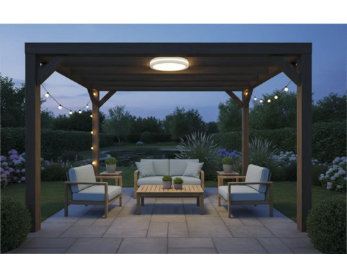 Pergola so záhradným nábytkom, stropným svietidlom a svetelnou reťazou v záhrade za súmraku.
