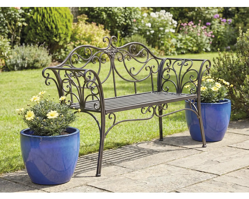 Ozdobná kovová záhradná lavička s kvetináčmi na záhradnej terase