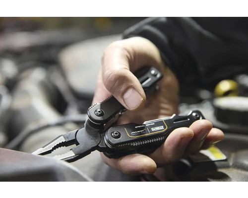 Multifunkčné náradie DeWalt McLaren Special Edition s kliešťami v ruke osoby pred motorom.