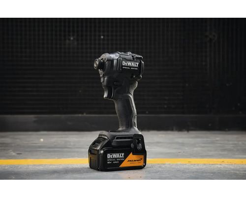 Akumulátorový rázový uťahovák DeWALT Special Edition McLaren s 18 Volt 4 ampérhodinovou batériou stojaci na sivej podlahe.