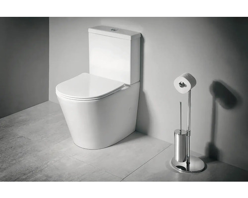 Stojace WC kombi z keramiky s nádržkou a sedadlom vedľa chrómovaného stojana na toaletný papier a WC kefy v kúpeľni.