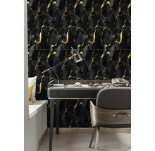 Moderný pracovný priestor s čiernym stolom a obkladmi v mramorovom vzhľade so zlatým žilkovaním.