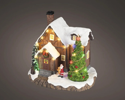 Miniatúrny vianočný domček z dreva so zasneženou strechou, osvetleným stromčekom a malou figúrkou Santa Clausa.