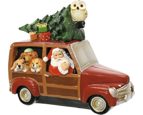 Vianočná figúrka Santa Claus za volantom červeného auta s tromi psami, vianočným stromčekom, darčekmi a sovou na streche.