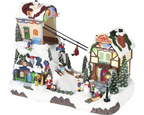 LED osvetlená vianočná dedinka s pohyblivým lyžiarskym vlekom, zasneženými domami, jedličkami a figúrkami ako Santa Claus a lyžiari.