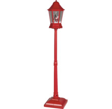 Červená vianočná pouličná lampa s efektom snehovej gule, figúrkou Santa Clausa a vianočným stromčekom.