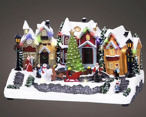Zasnežená vianočná krajina s osvetlenými miniatúrnymi domami, vianočným stromčekom, saňami, sobom a figúrkami.