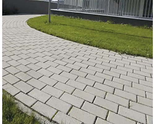 Zakrivený záhradný chodník z obdĺžnikovej betónovej dlažby vedľa trávnika.