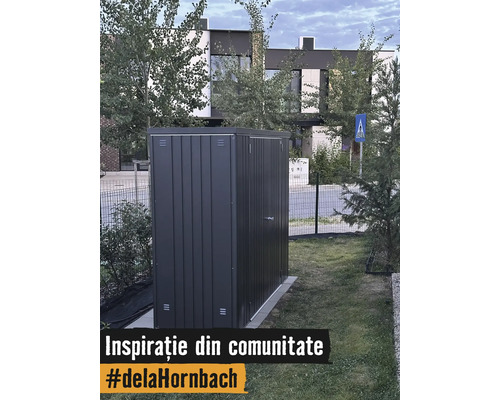Moderný kovový záhradný domček v tmavosivej farbe na trávniku v záhrade pred domom.