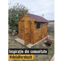 Malý drevený záhradný domček so sedlovou strieškou a otvorenými dverami na betónovej doske v záhrade.