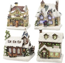 Štyri vianočné miniatúrne domy pokryté snehom a osvetlené.