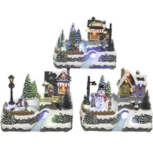 Zimná scéna miniatúrnej dediny s osvetlenými domami, stromami a figúrkami