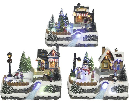 Zimná scéna miniatúrnej dediny s osvetlenými domami, stromami a figúrkami