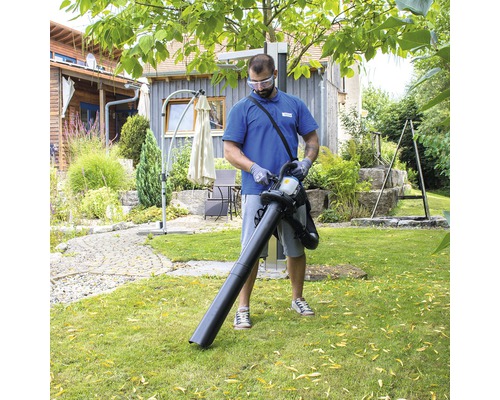 Muž používa vysávač lístia v záhrade.