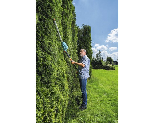 Muž strihá živý plot pomocou nožníc na živý plot