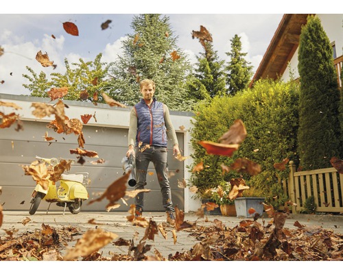 Muž používa fúkač lístia na odstránenie lístia na dvore.