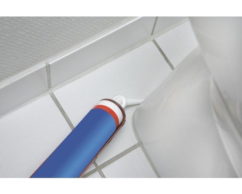 Sanitárna silikónová kartuša tmelu vedľa toalety na kúpeľňových dlaždiciach