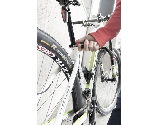 Detailný záber na bicykel, ktorého sedlovka je nastavovaná nástrojom.