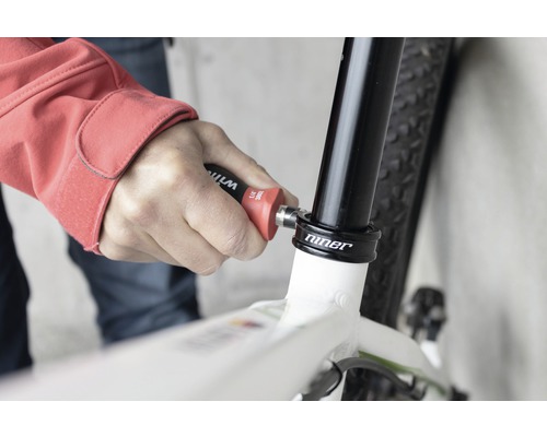Osoba používa náradie na bicykli na opravu.